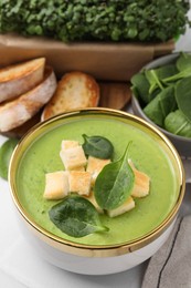 Delicious spinach cream soup with croutons in bowl on table