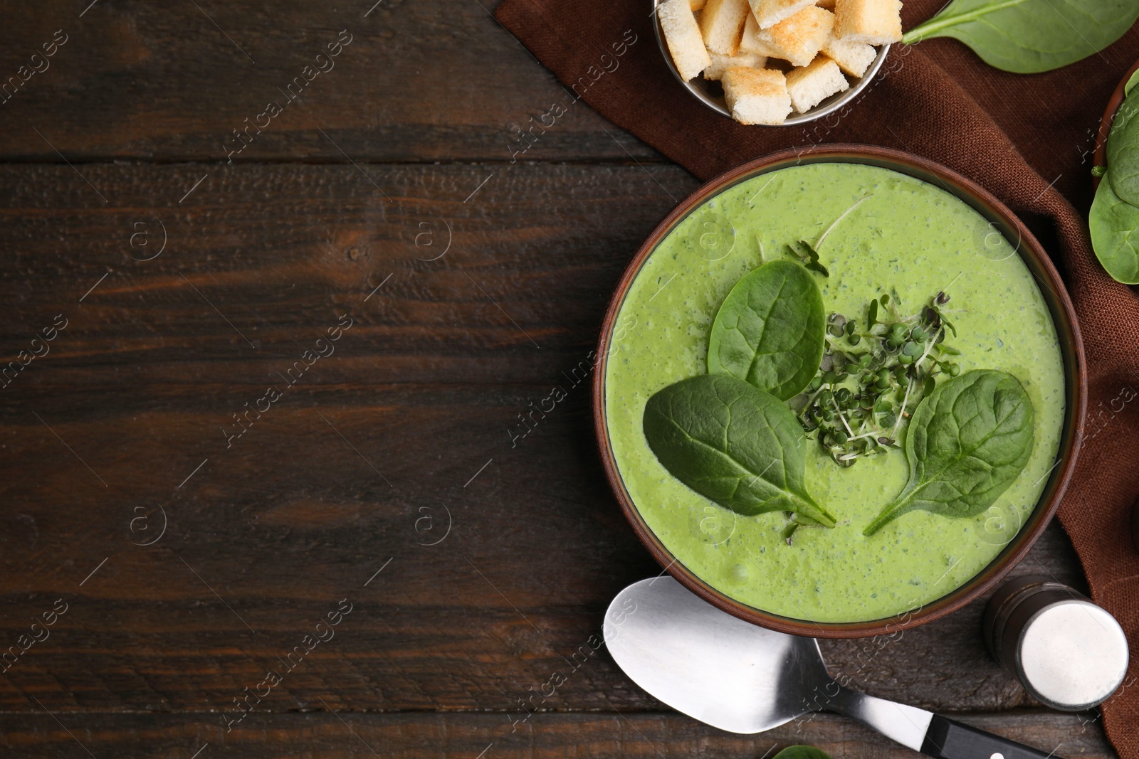 Photo of Delicious spinach cream soup served on wooden table, flat lay. Space for text