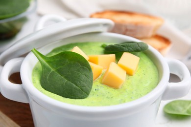 Photo of Delicious spinach cream soup with cheese in bowl on light table, closeup