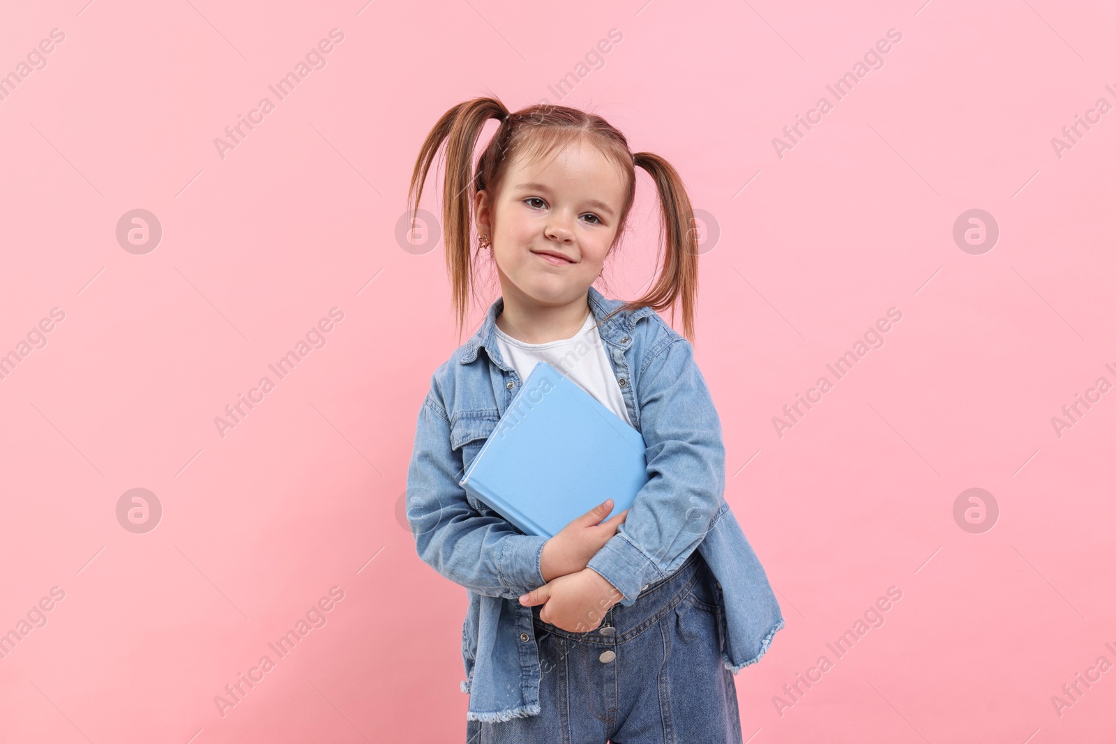 Photo of Cute little girl with book on pink background