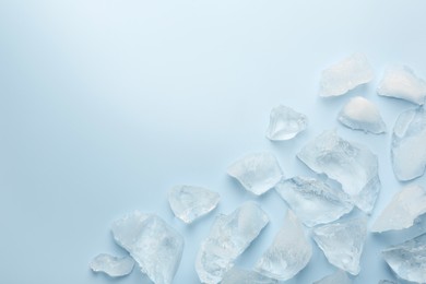 Pieces of crushed ice on light blue background, top view. Space for text