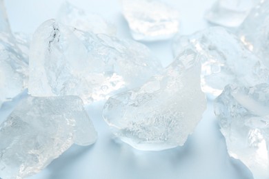 Photo of Pieces of crushed ice on light blue background, closeup