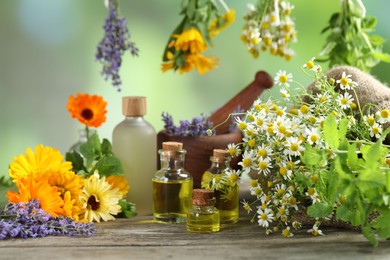 Photo of Different flowers, bottles of essential oils, mint mortar and pestle on wooden table