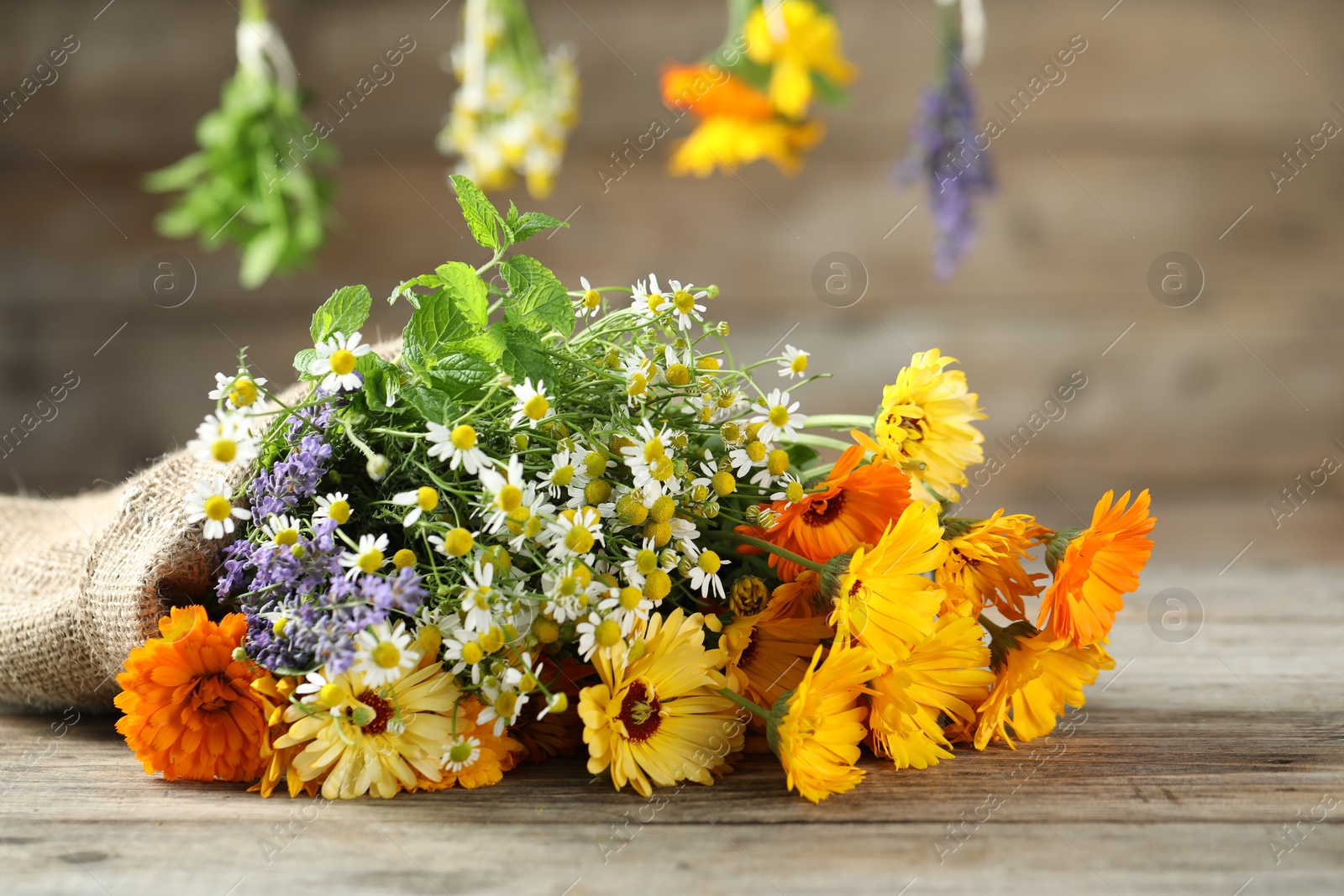 Photo of Beautiful calendula flowers, lavender, chamomiles and mint on wooden table