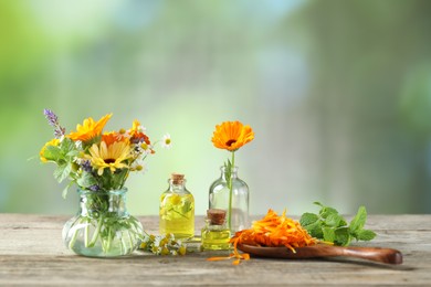 Photo of Different flowers, mint and bottles of essential oils on wooden table