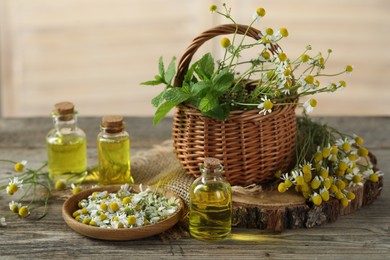 Photo of Beautiful chamomile flowers, bottles of essential oils and mint on wooden table