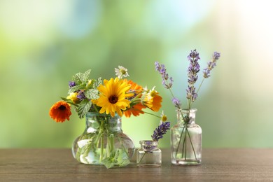 Photo of Different flowers in glass bottles on wooden table