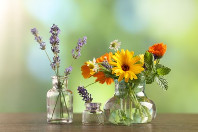 Photo of Different flowers in glass bottles on wooden table