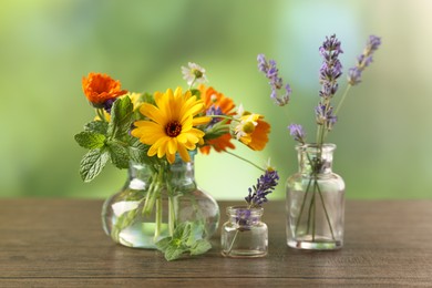 Photo of Different flowers in glass bottles on wooden table