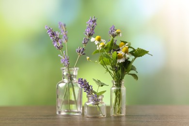 Different flowers in glass bottles on wooden table