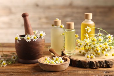 Photo of Different flowers and bottles of essential oils on wooden table