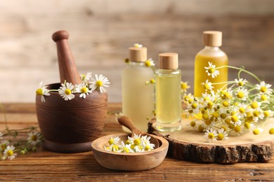 Different flowers and bottles of essential oils on wooden table