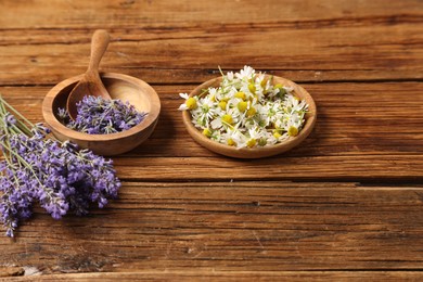 Photo of Different flowers in bowls and spoon on wooden table
