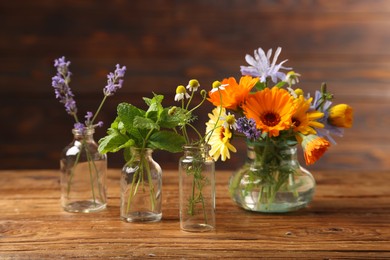 Different flowers in glass bottles on wooden table
