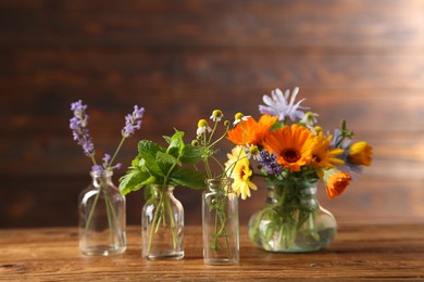 Photo of Different flowers in glass bottles on wooden table