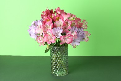 Photo of Beautiful alstroemeria flowers in vase on green background