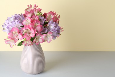 Photo of Beautiful alstroemeria flowers in vase on color background, space for text