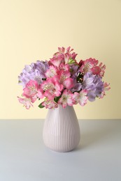 Beautiful alstroemeria flowers in vase on color background