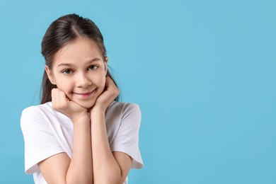 Portrait of beautiful girl on light blue background, space for text