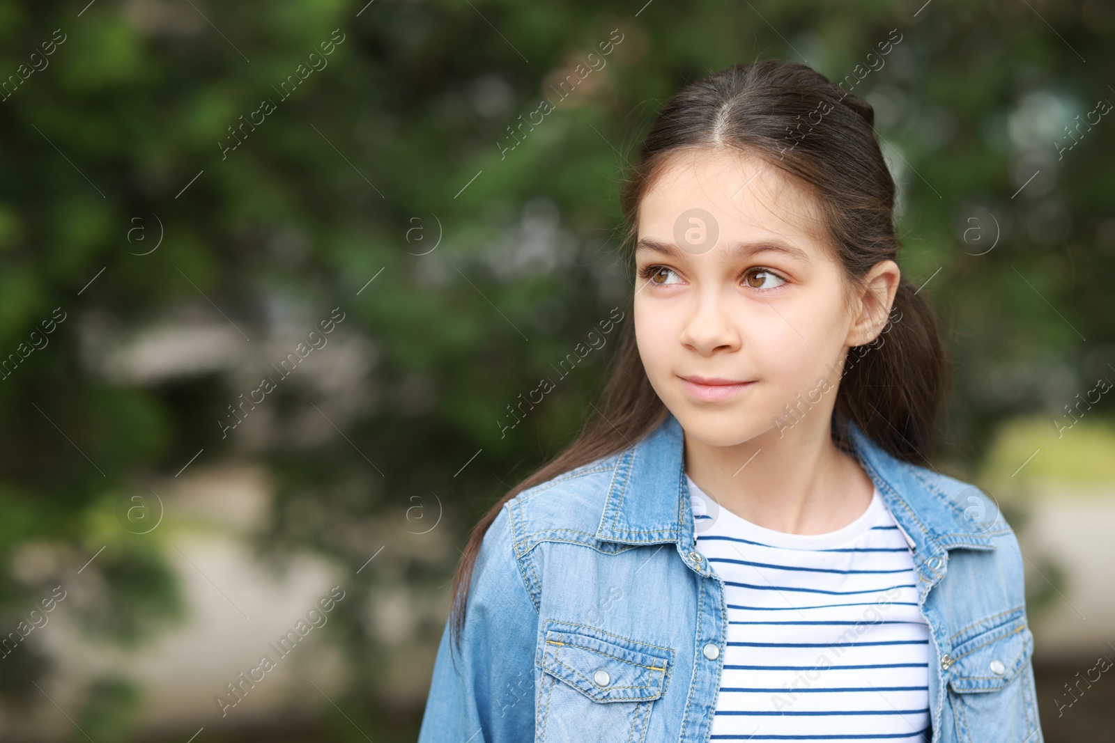 Photo of Portrait of cute little girl outdoors, space for text