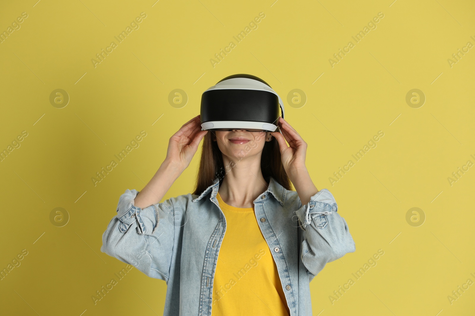 Photo of Woman using virtual reality headset on yellow background