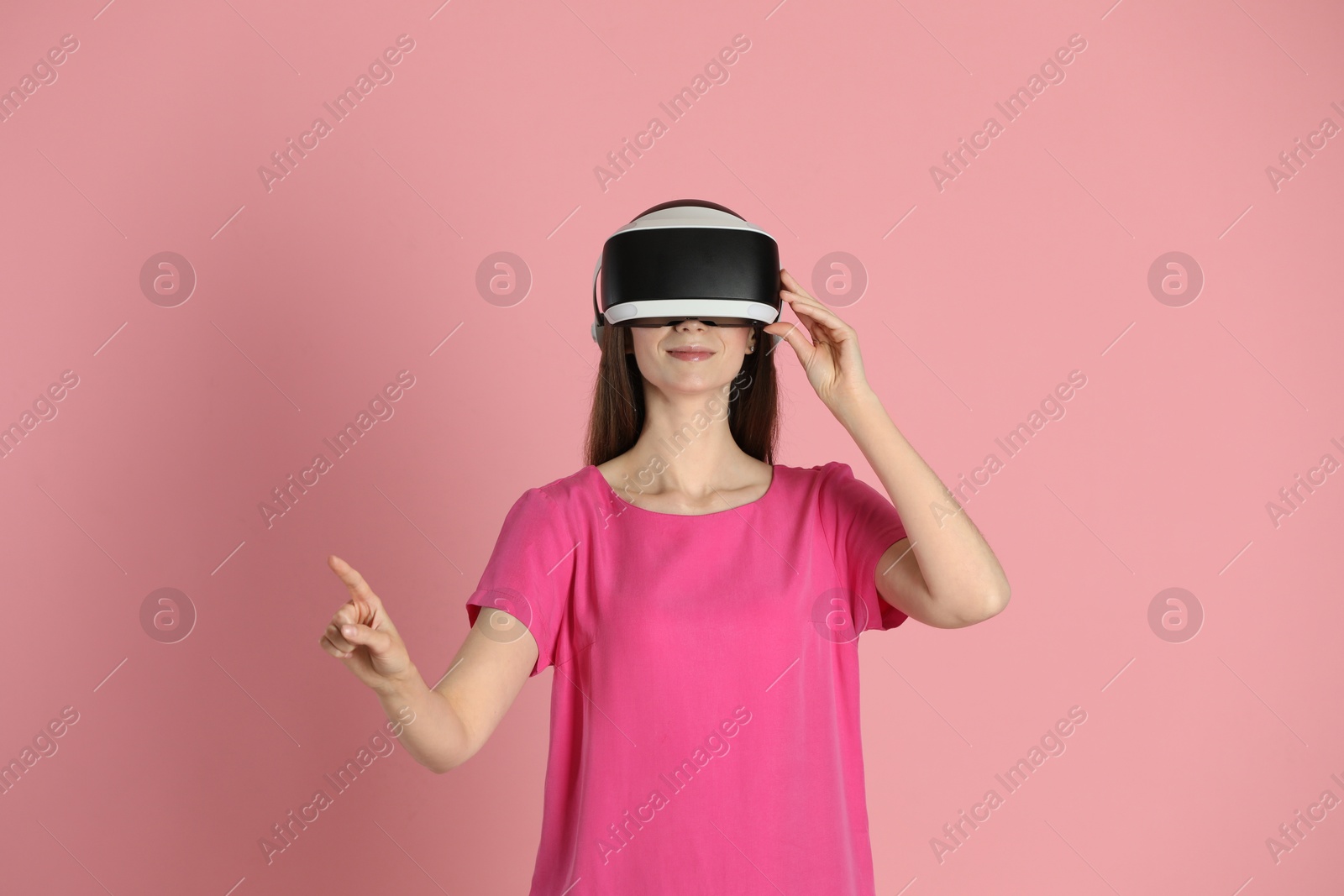 Photo of Woman using virtual reality headset on pink background
