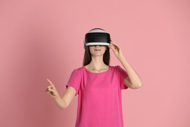 Photo of Woman using virtual reality headset on pink background