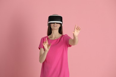Smiling woman using virtual reality headset on pink background