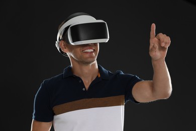 Photo of Smiling man using virtual reality headset on black background
