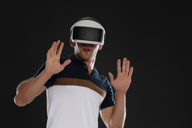 Photo of Surprised man using virtual reality headset on black background