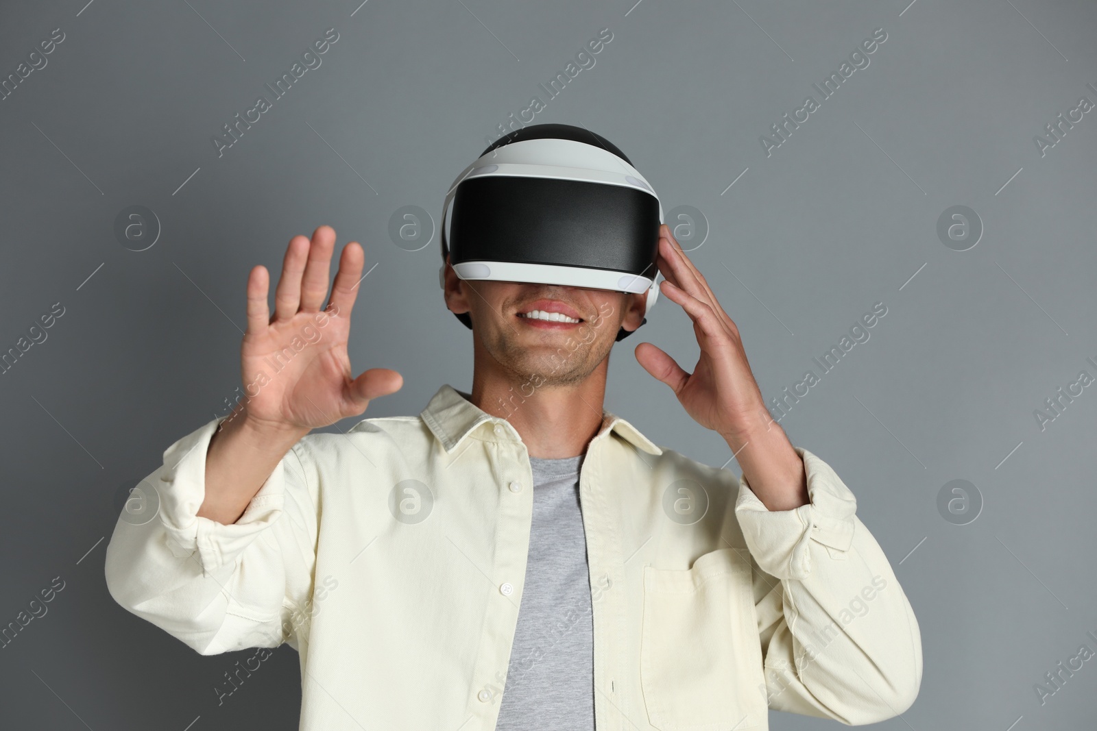 Photo of Smiling man using virtual reality headset on gray background