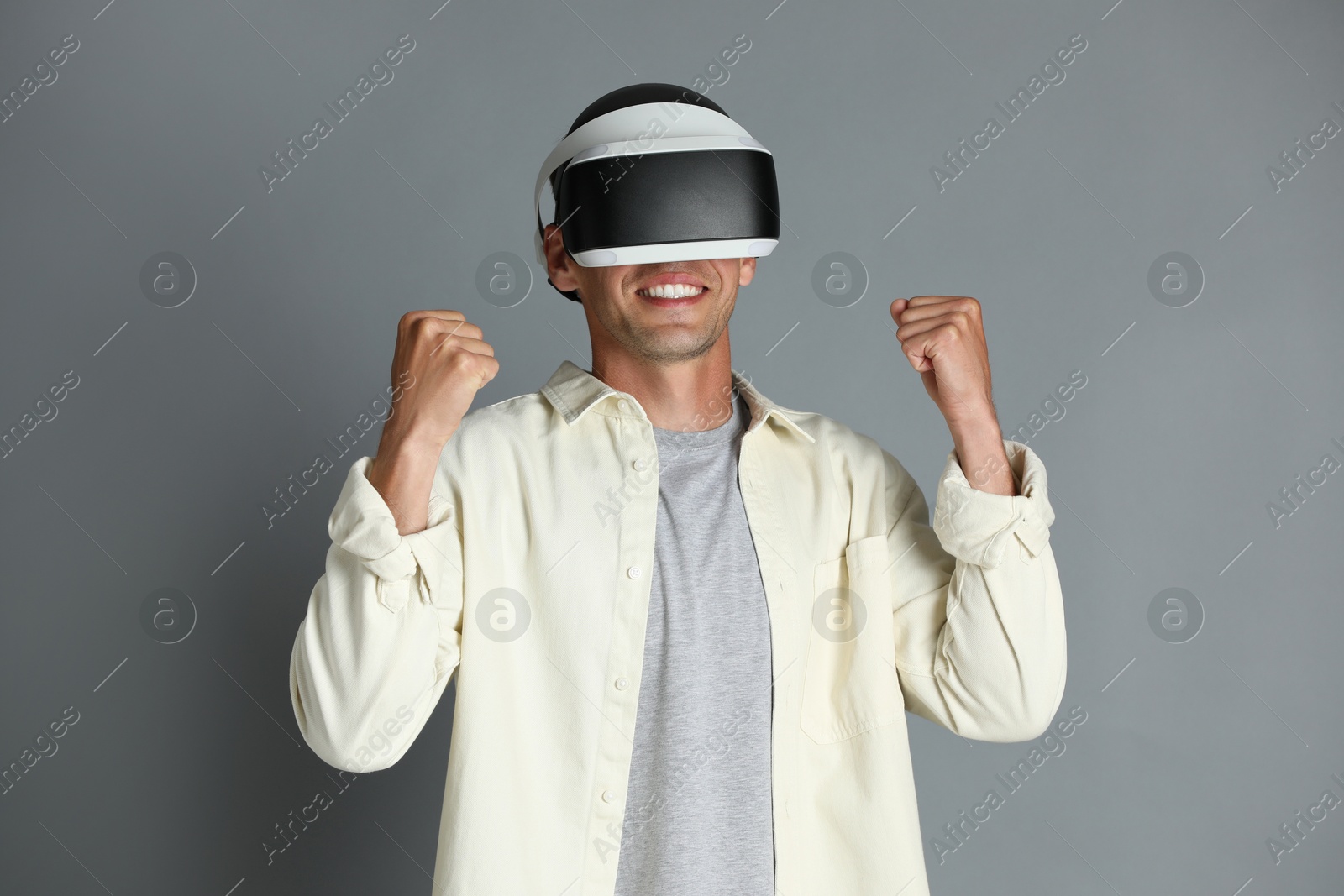 Photo of Smiling man using virtual reality headset on gray background