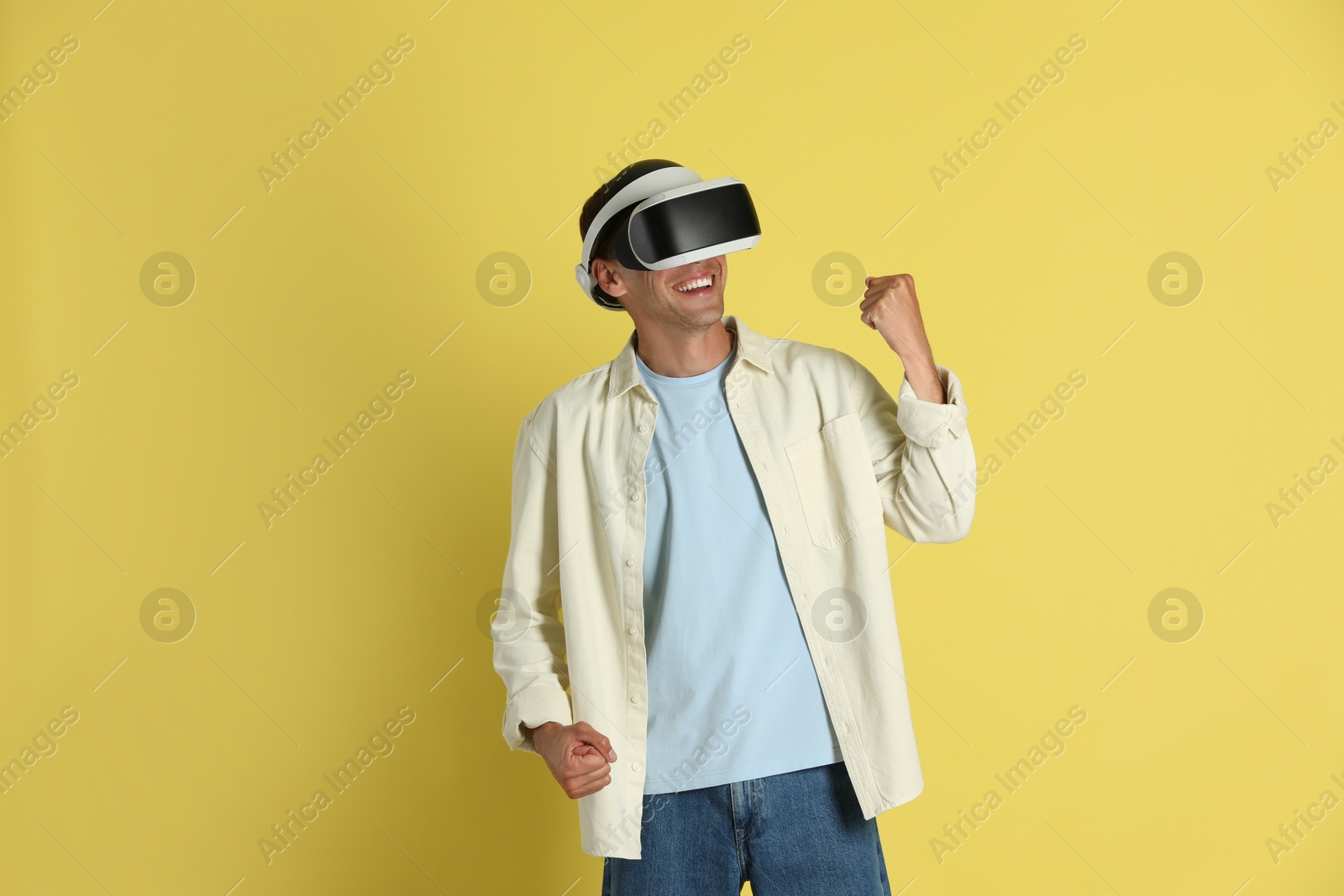 Photo of Smiling man using virtual reality headset on yellow background