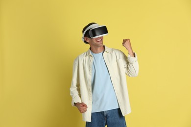 Photo of Smiling man using virtual reality headset on yellow background
