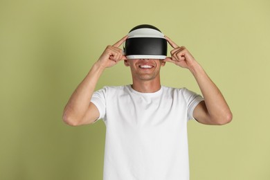 Photo of Smiling man using virtual reality headset on light green background