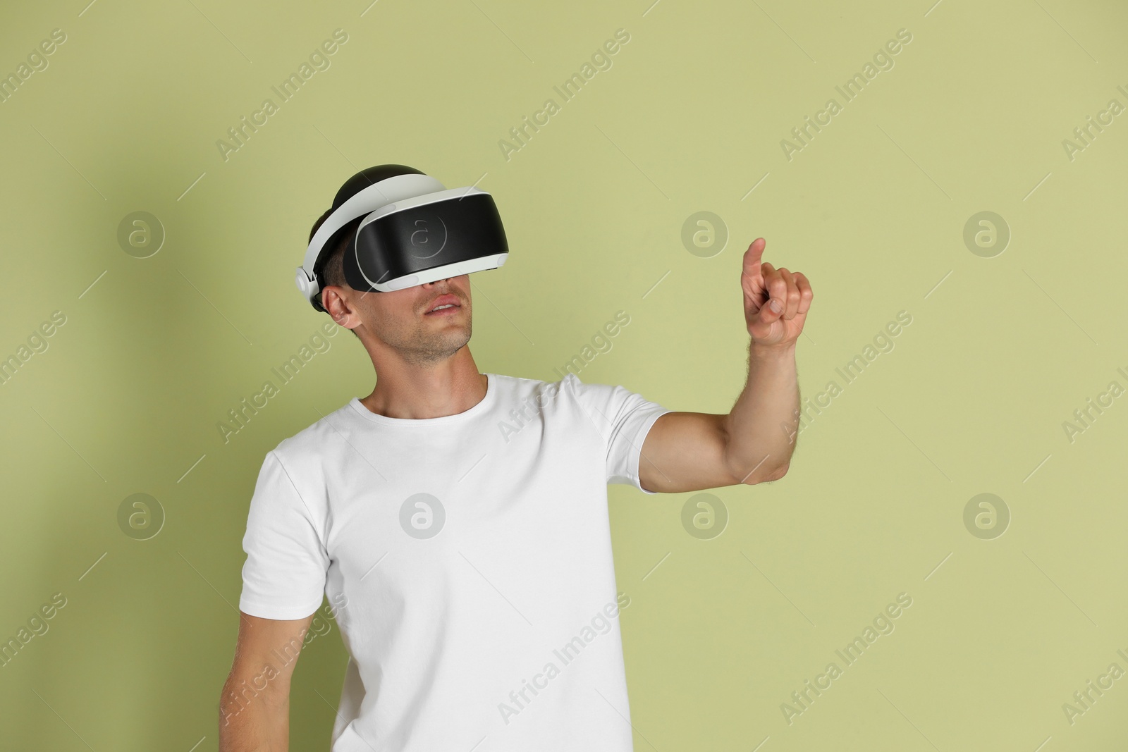 Photo of Man using virtual reality headset on light green background
