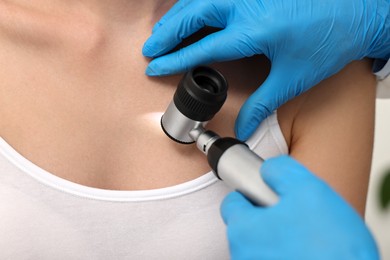 Dermatologist with dermatoscope examining patient, closeup view