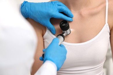 Dermatologist with dermatoscope examining patient, closeup view