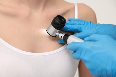 Dermatologist with dermatoscope examining patient, closeup view