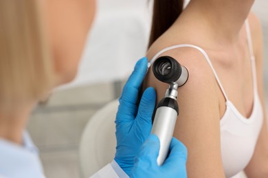 Photo of Dermatologist with dermatoscope examining patient in clinic, closeup