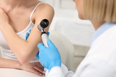 Photo of Dermatologist with dermatoscope examining patient in clinic, closeup