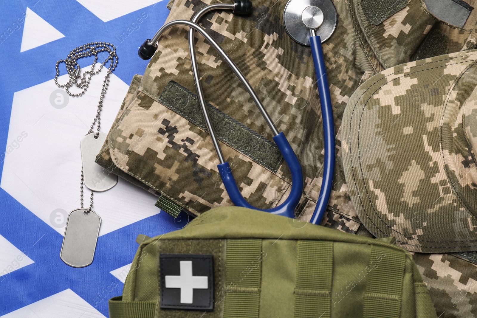 Photo of Stethoscope, first aid kit, tags and military uniform on flag of Israel, flat lay