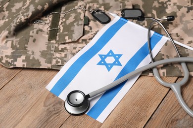 Stethoscope, flag of Israel, tags and military uniform on wooden table, closeup