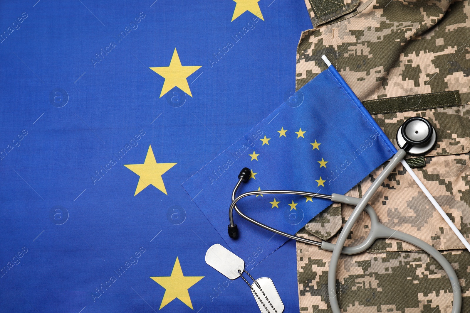 Photo of Stethoscope, tags and military uniform on flag of European Union, top view