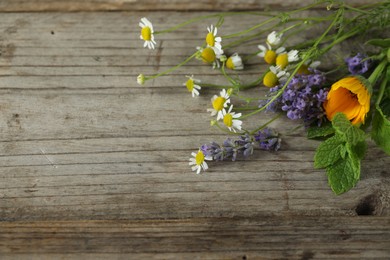 Photo of Beautiful calendula, lavender, mint and chamomile flowers on wooden table, space for text
