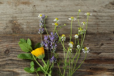 Photo of Beautiful calendula, lavender, mint and chamomile flowers on wooden table, flat lay