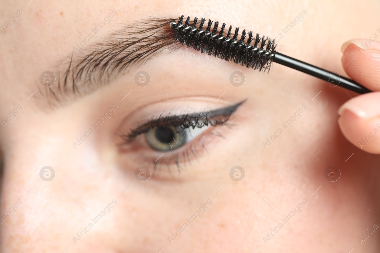 Photo of Young woman with spoolie brush, closeup. Eyebrow correction