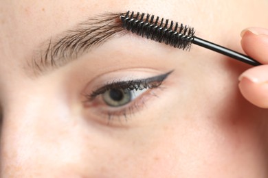Young woman with spoolie brush, closeup. Eyebrow correction