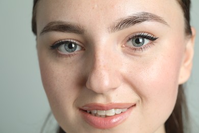 Photo of Young woman with beautiful eyebrows on light background, closeup