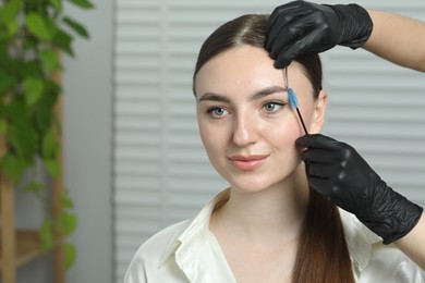 Photo of Beautician making eyebrow correction to young woman in beauty salon, closeup